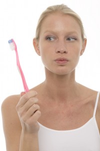 woman holding toothbrush skeptically