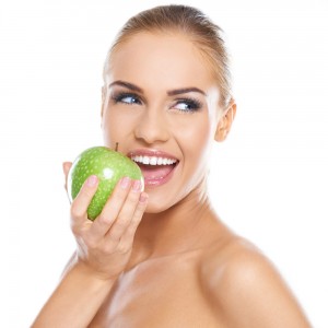 woman with bright smile eating an apple